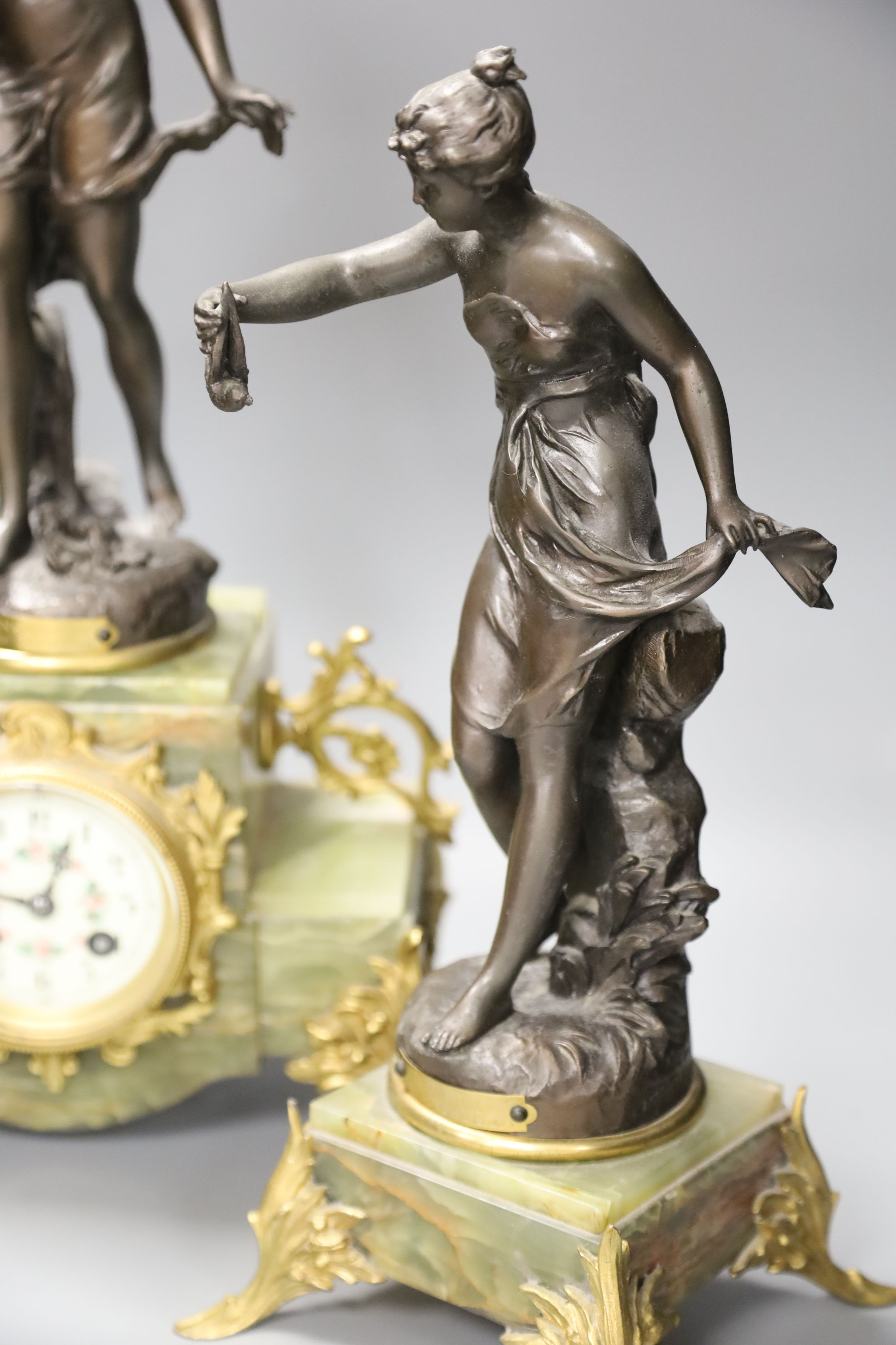 A French onyx and spelter figural clock garniture after Ferrand, plaques read Improvisateur Prisonniere and Sensitive, height 50cm